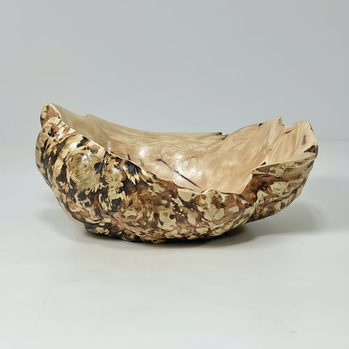 Decorative burl bowl with gold and brown patterns on a gray background